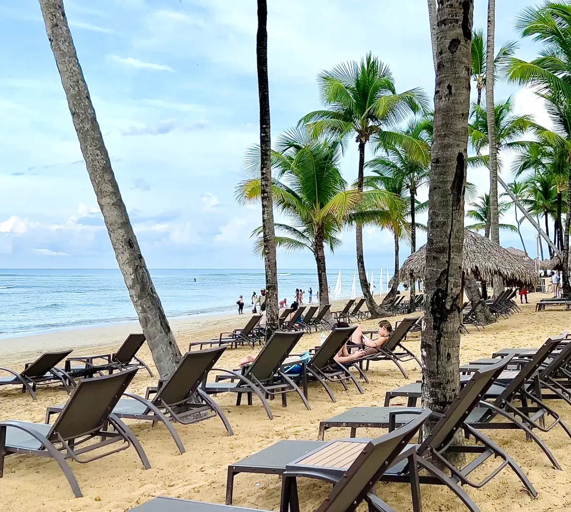 The beach at Breathless Punta Cana at first light, empty, with the loungers still stacked.