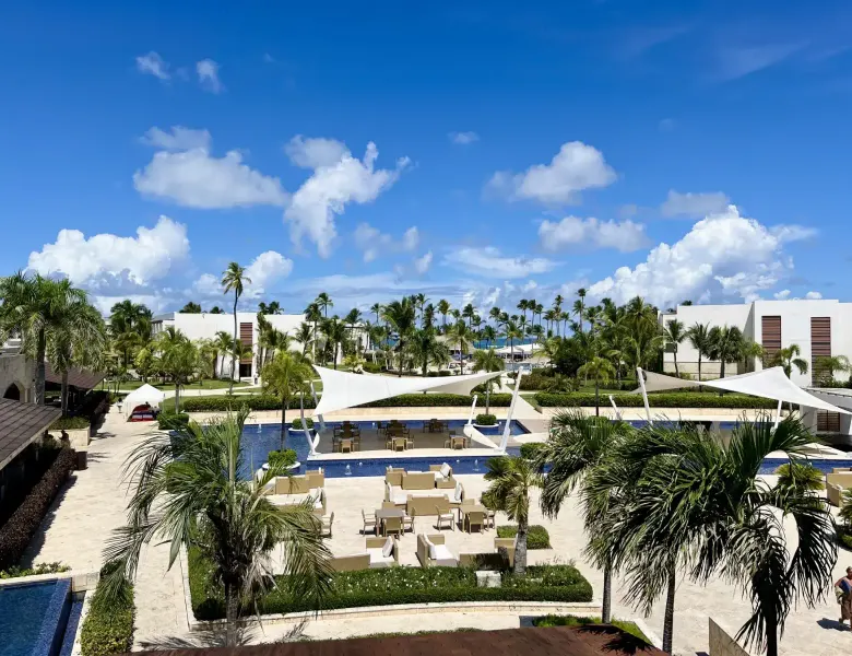 Pool area with palm trees, lounge chairs, and white shade structures