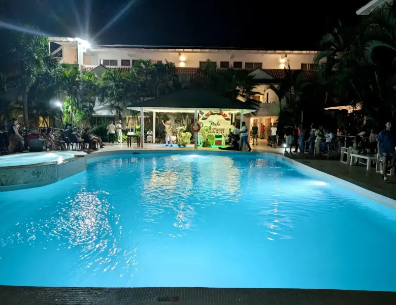 Pool at night with people around a covered stage area