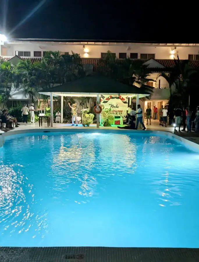 Pool at night with people around a covered stage area