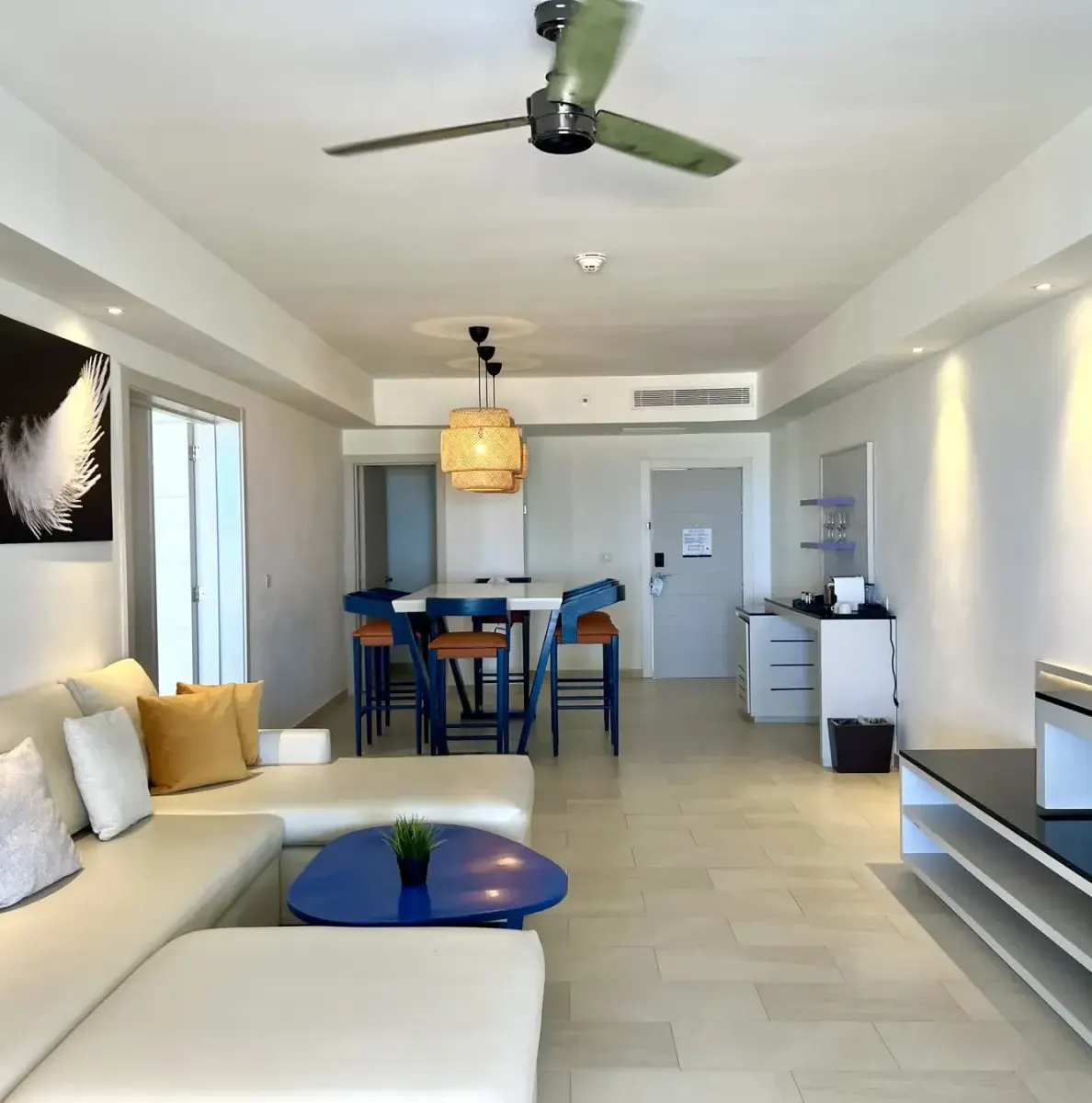 Living room with sofa, table, chairs, TV, and ceiling fan