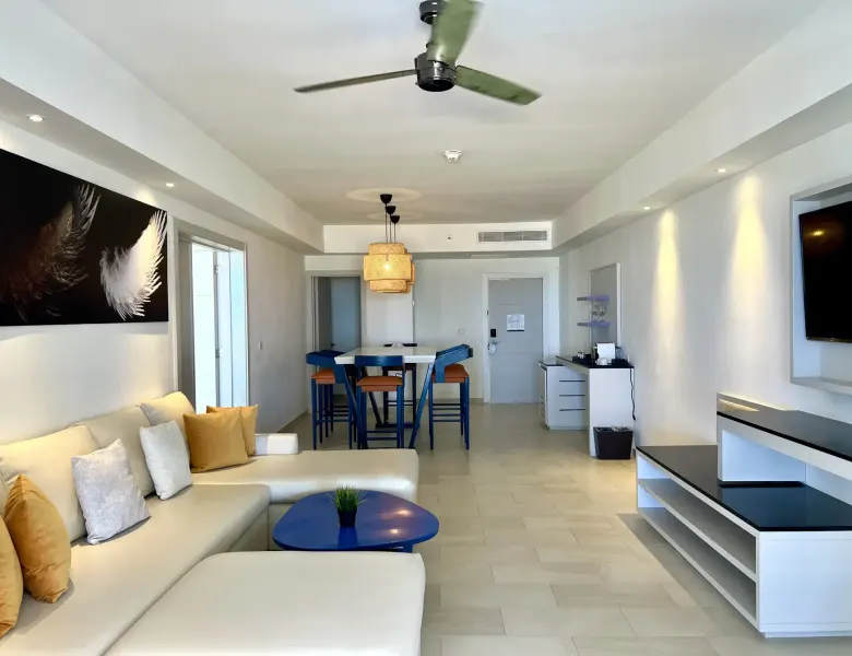 Living room with sofa, table, chairs, TV, and ceiling fan