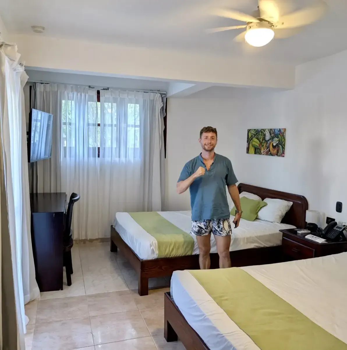 Two beds, a man, a TV, a desk, and a painting
