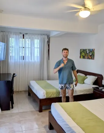 Two beds, a man, a TV, a desk, and a painting