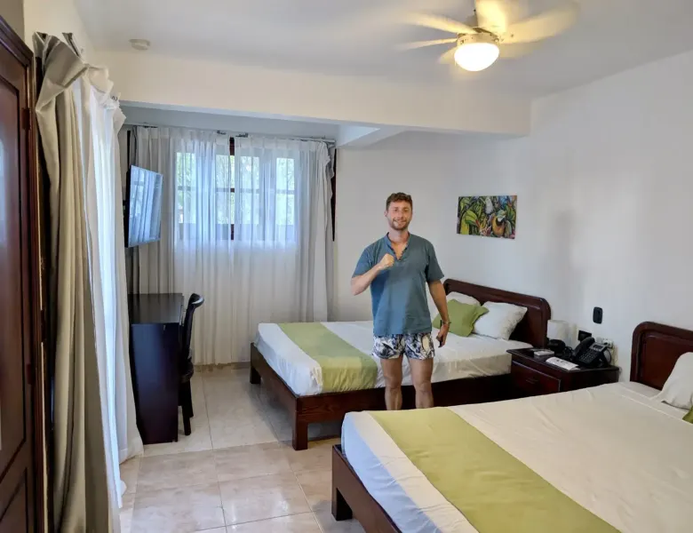 Two beds, a man, a TV, a desk, and a painting