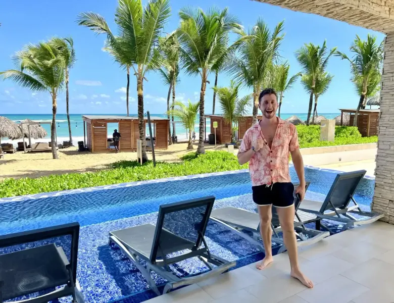 Man standing by pool with beach and palm trees in background