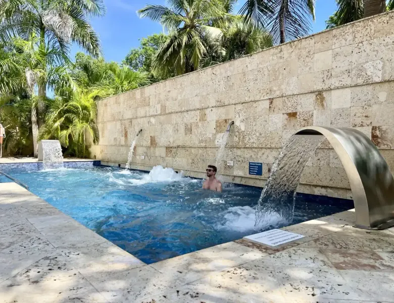 Man in a pool with waterfalls and palm trees
