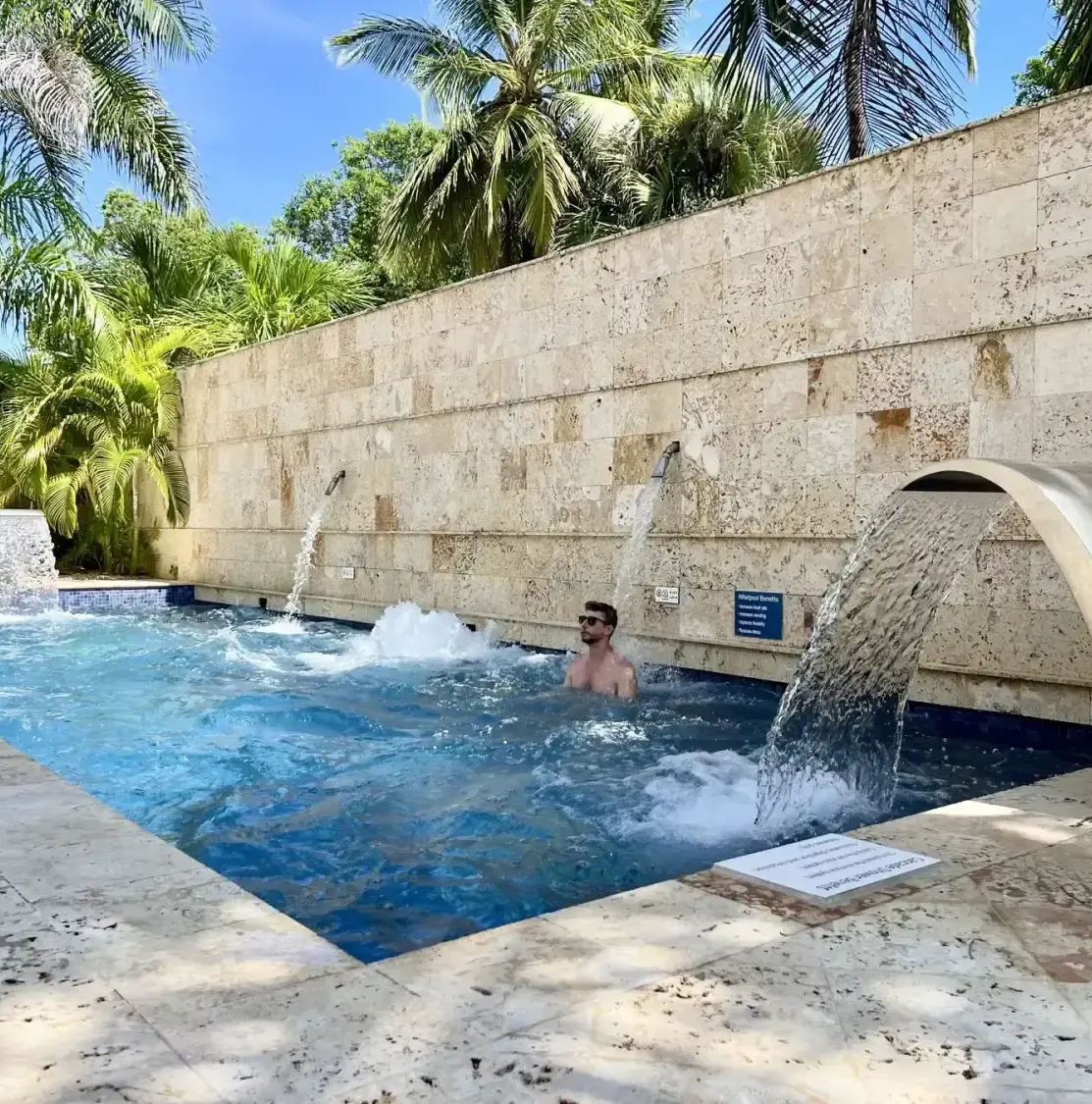 Man in a pool with waterfalls and palm trees