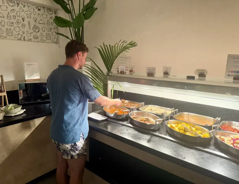 Man serving himself food from a buffet counter with multiple dishes