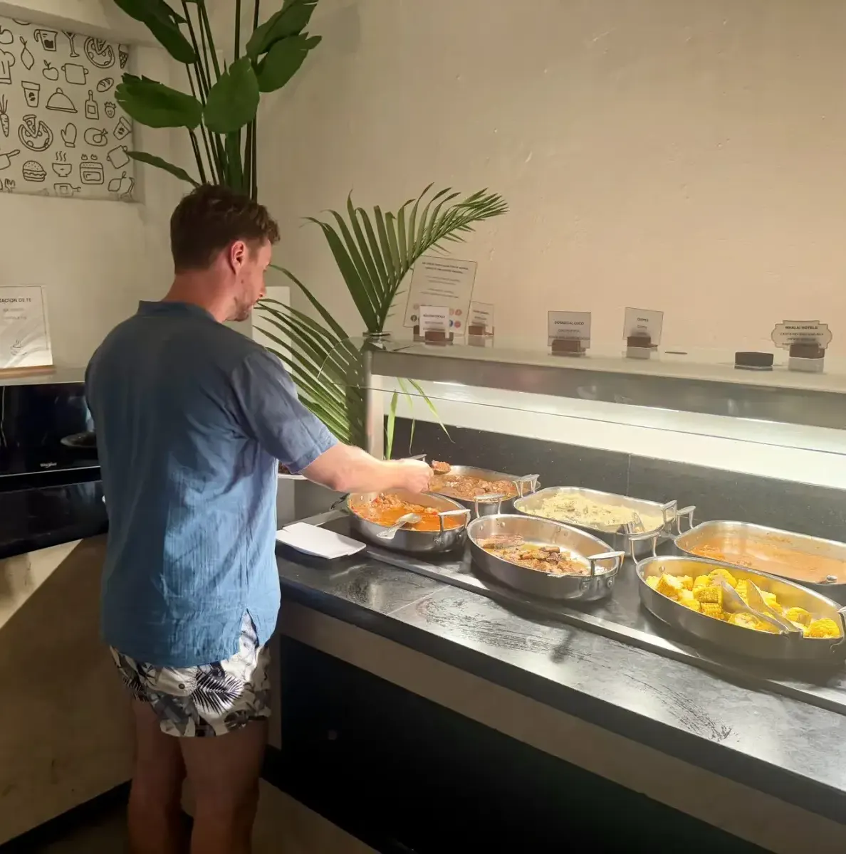 Man serving himself food from a buffet counter with multiple dishes