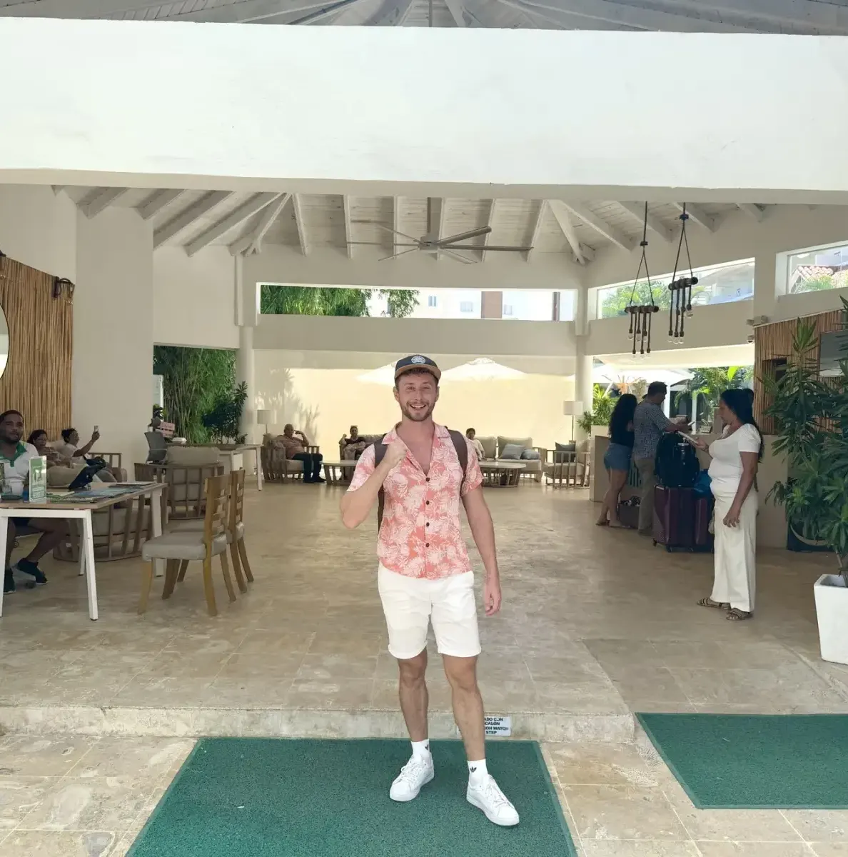 Man in pink shirt standing in resort lobby with people in background
