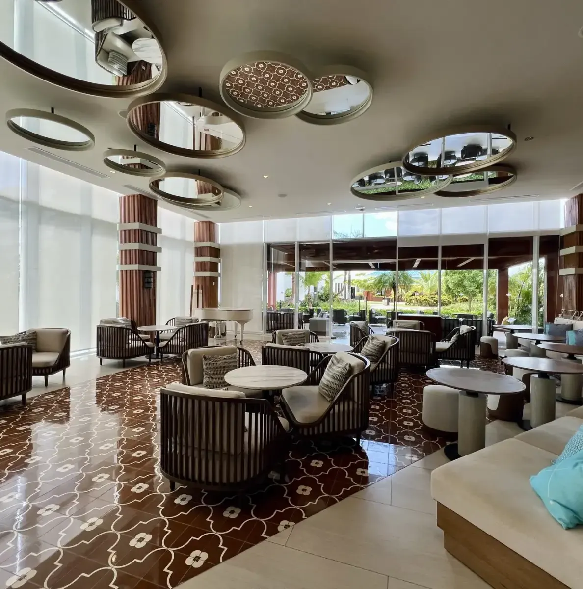 Lobby with tables, chairs, mirrors, and large windows