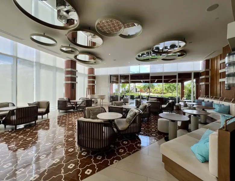 Lobby with tables, chairs, mirrors, and large windows
