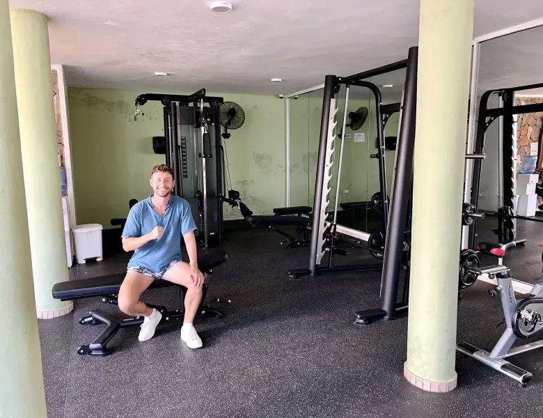 Man sitting on bench in gym with exercise equipment