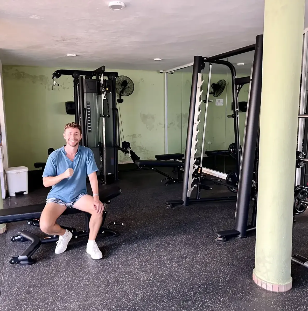 Man sitting on bench in gym with exercise equipment