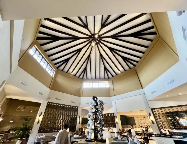 Lobby with a large ceiling, sculpture, and people in a resort