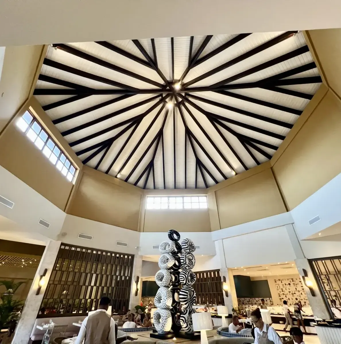 Lobby with a large ceiling, sculpture, and people in a resort