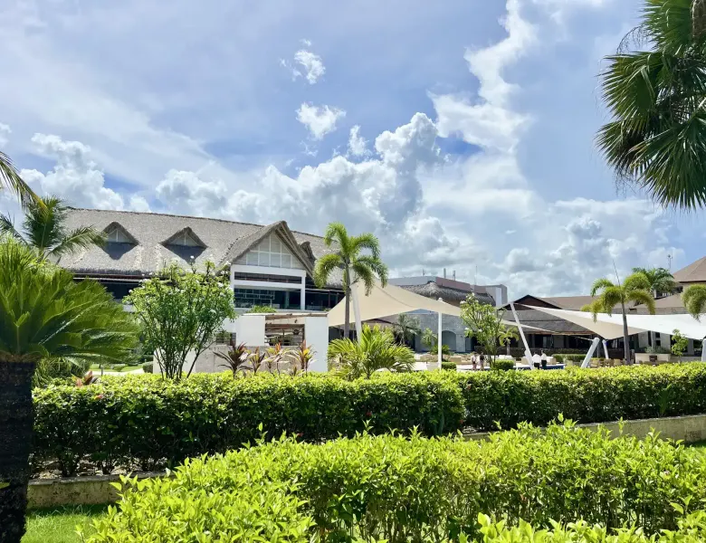 resort buildings, hedges, palm trees, white canopy, cloudy sky