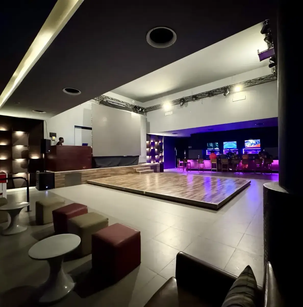 stage, seating, tables, bar area, screens, lighting