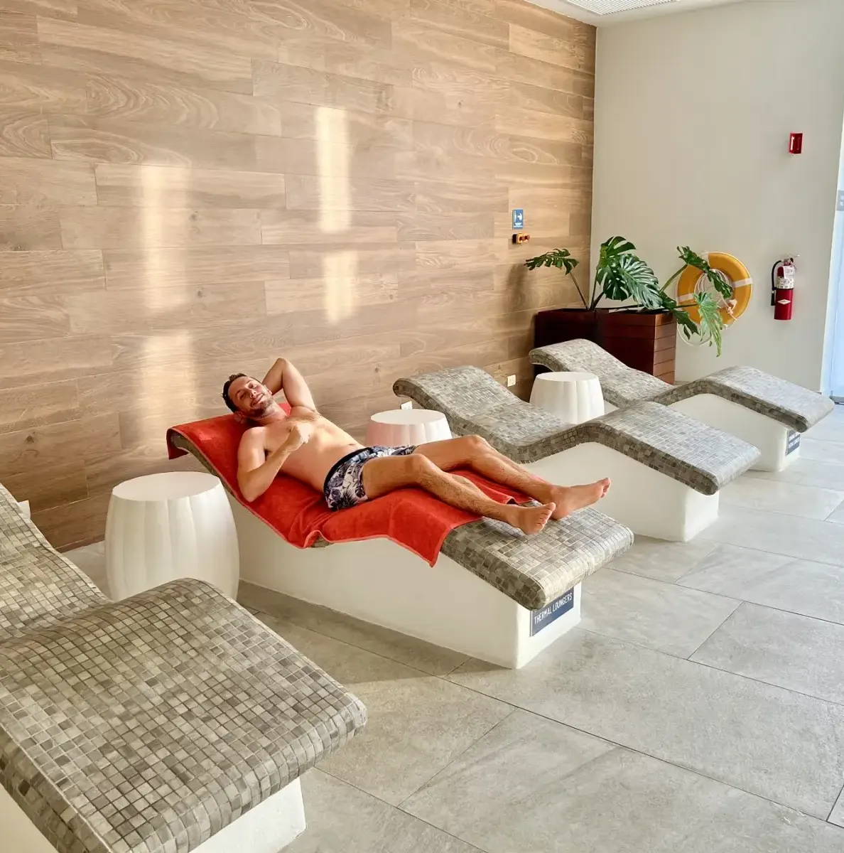 Man lying on lounge chair with red towel in spa area