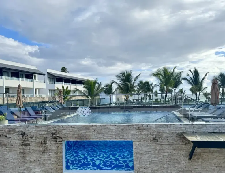Pool with lounge chairs, palm trees, and resort buildings