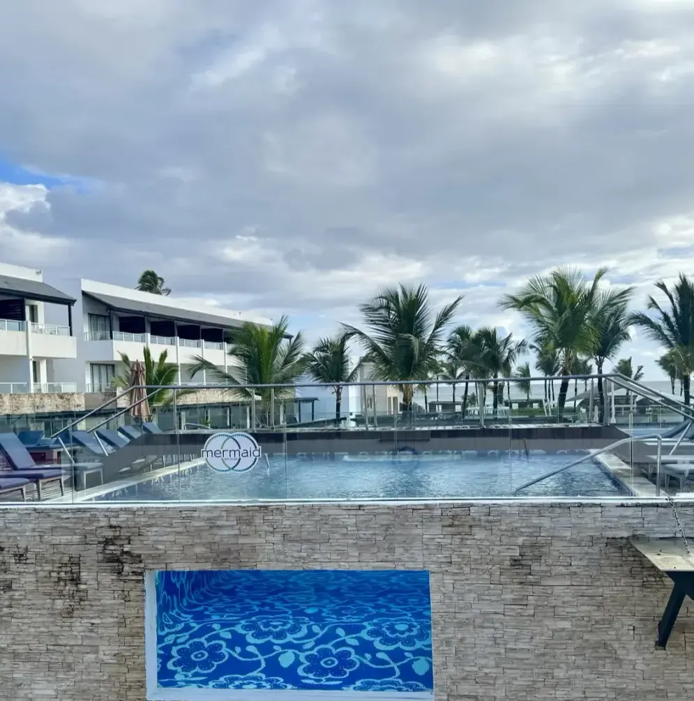 Pool with lounge chairs, palm trees, and resort buildings