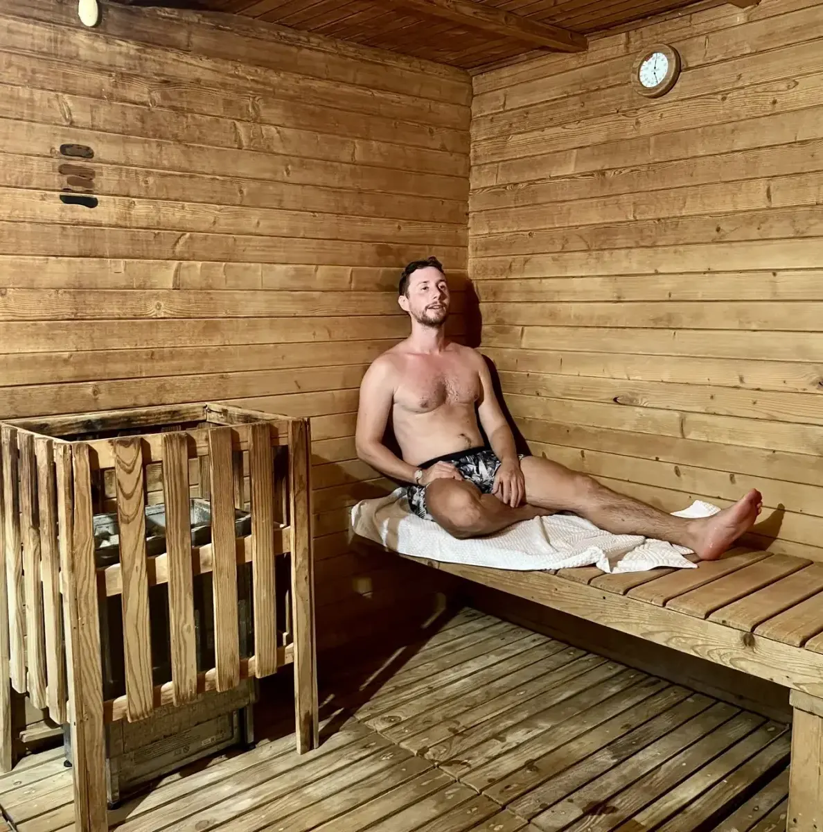 Man sitting on wooden bench in sauna with wood walls and heater
