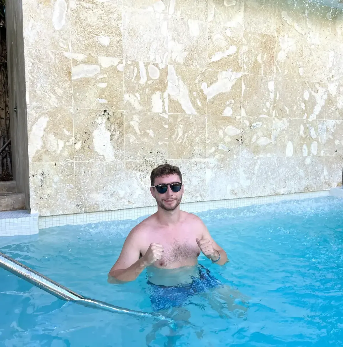 Man in pool with tiled wall and metal handrail