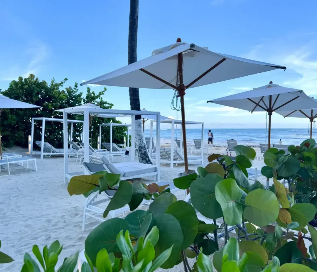 The beach at whala!bávaro, a parasol and two loungers on the sand.